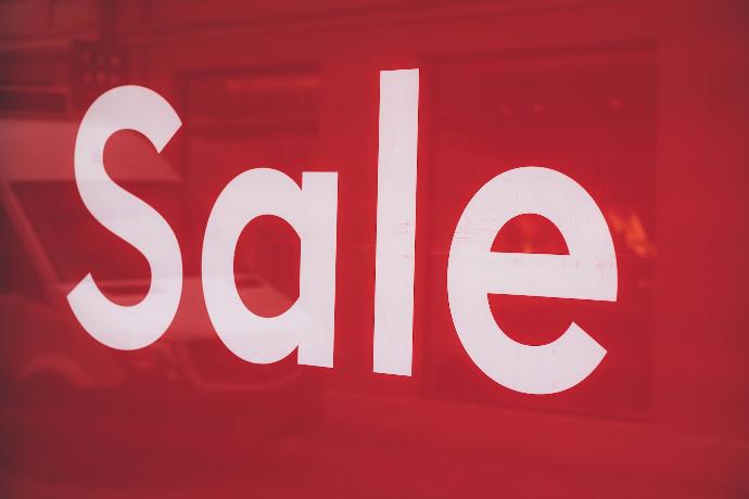 a close up of a red sale sign with a van in the background